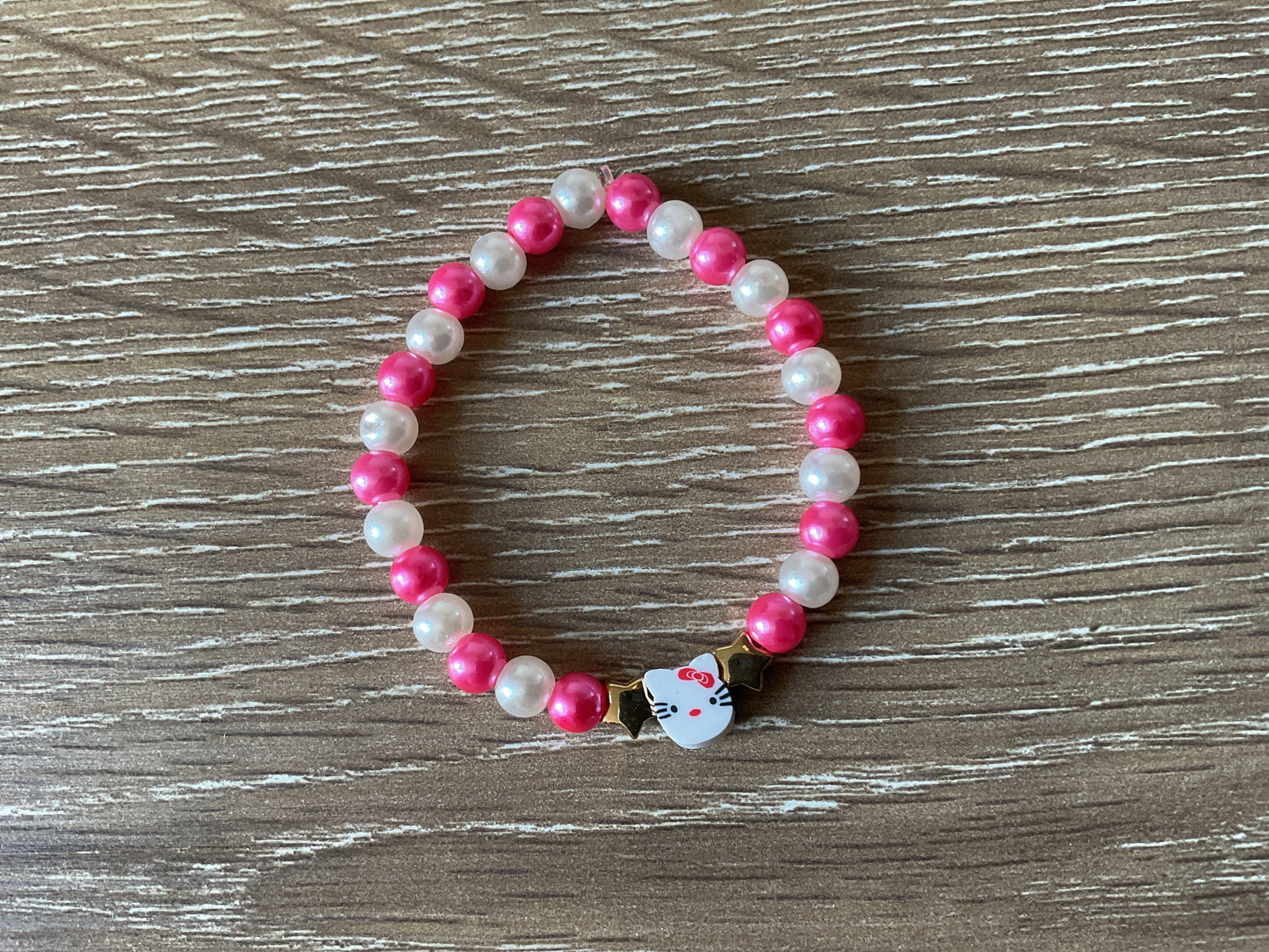 Pink and white ‘Hello Kitty’ bracelet with two gold stars