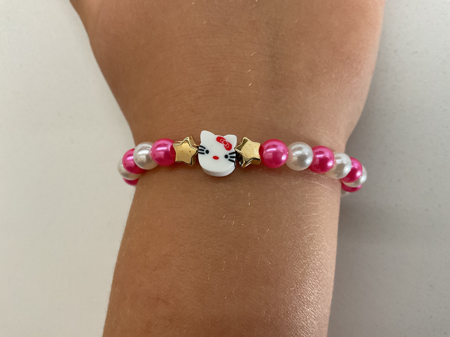 Pink and white ‘Hello Kitty’ bracelet with two gold stars